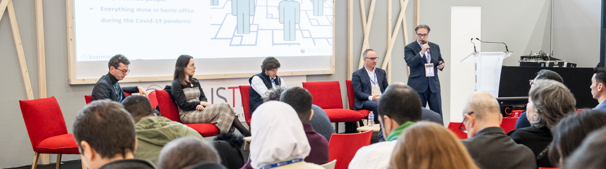 Table-ronde TRUSTECH avec plusieurs intervenants dont Andréa TOUCINHO, parlant de paiement devant une assemblée de visiteurs