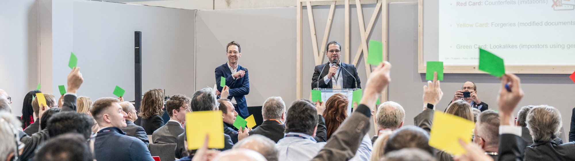 Attendees with papers to interact with two speakers on stage in the conference room