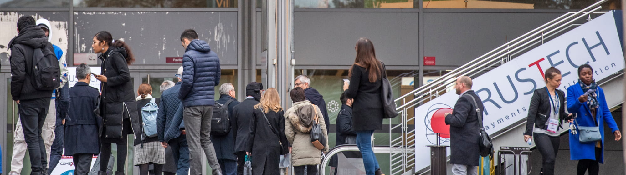 visiteurs à l'extérieur du pavillon, se dirigeant vers l'entrée de TRUSTECH