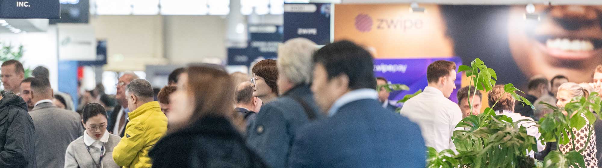 Visiteurs marchent dans les allées Trustech en regardant des stands