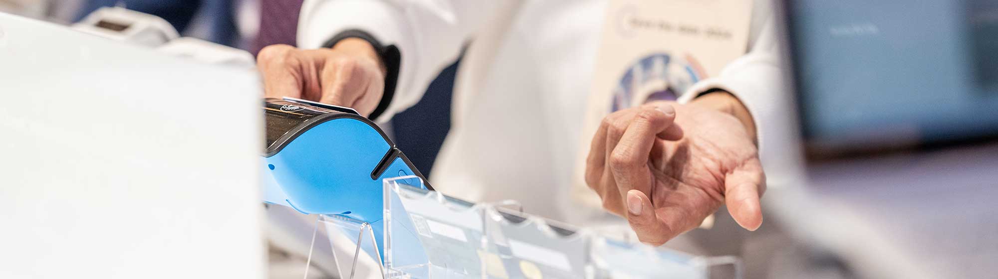 A person using an electronic payment terminal at a booth during the TRUSTECH event.