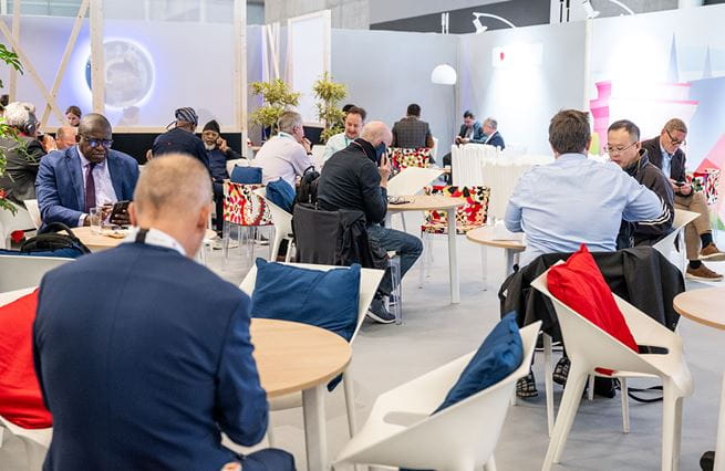 professionals working in the TRUSTECH VIP area. Some are using their computers, others are making phone calls or having meetings with other attendees.