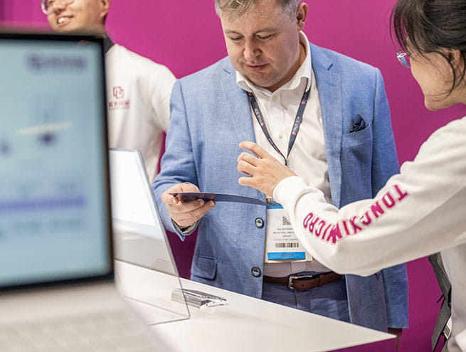 An exhibitor presenting an information brochure to a visitor