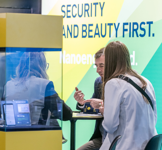 Participants in a business meeting at an exhibitor stand at TRUSTECH 2025 discussing security and identification solutions