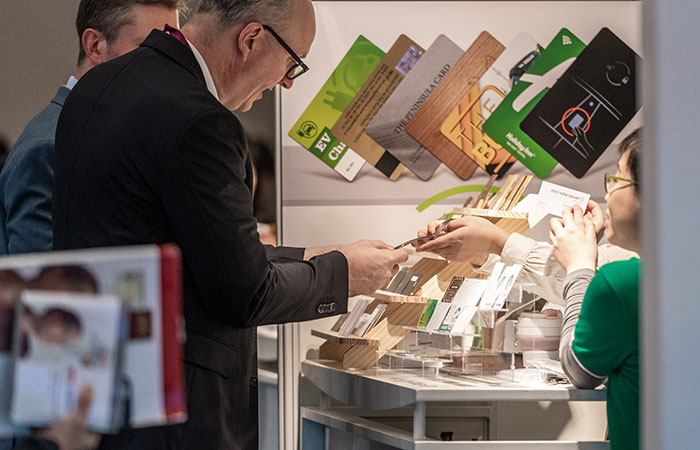 Visitor looking at personalised credit cards on an exhibitor booth at TRUSTECH