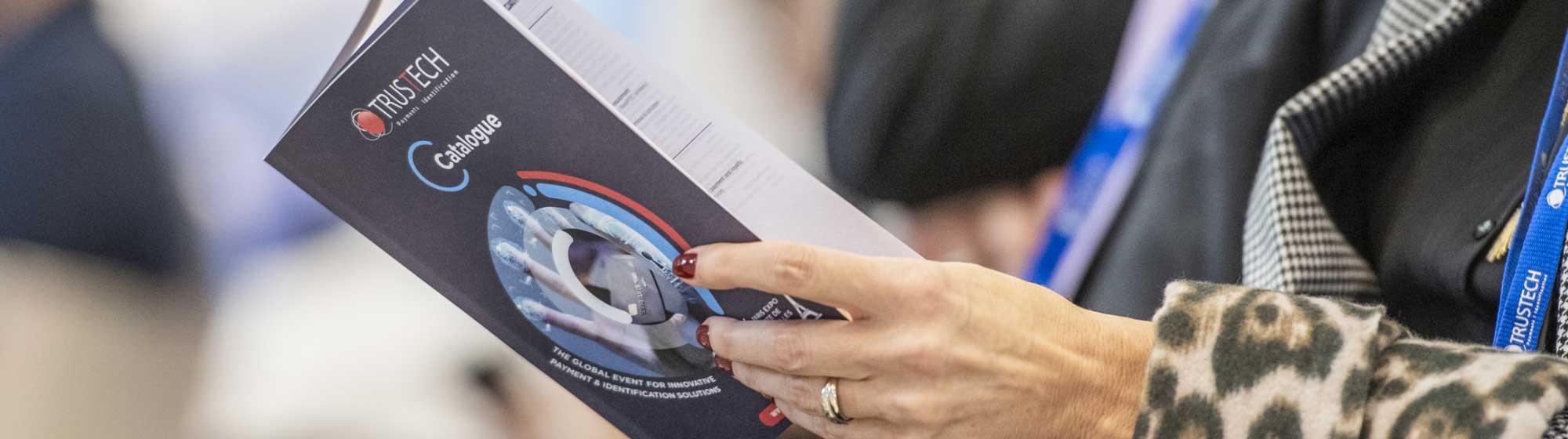 a seated woman flips through the Trustech event catalog