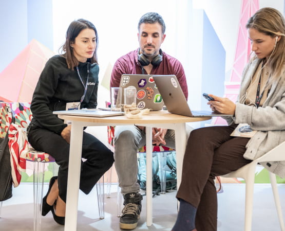 Professionnels travaillant dans l'Espace Vip TRUSTECH. Deux visiteurs consultent leur ordinateur et une autre passe un appel téléphonique